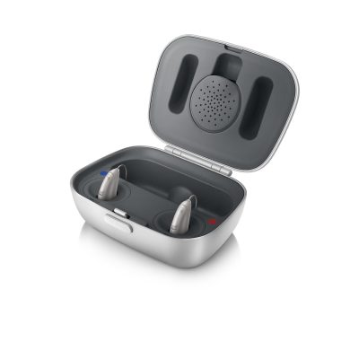 A Unitron Moxi R Charger is open, displaying two hearing aids in separate compartments with blue and red markers indicating left and right sides.
