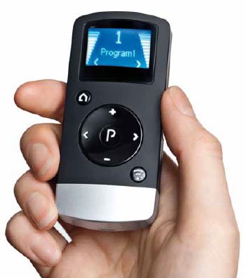 A hand holds a ReSound Remote Control 2, a small black device with a screen showing "1 Program1" and several circular control buttons below the display.
